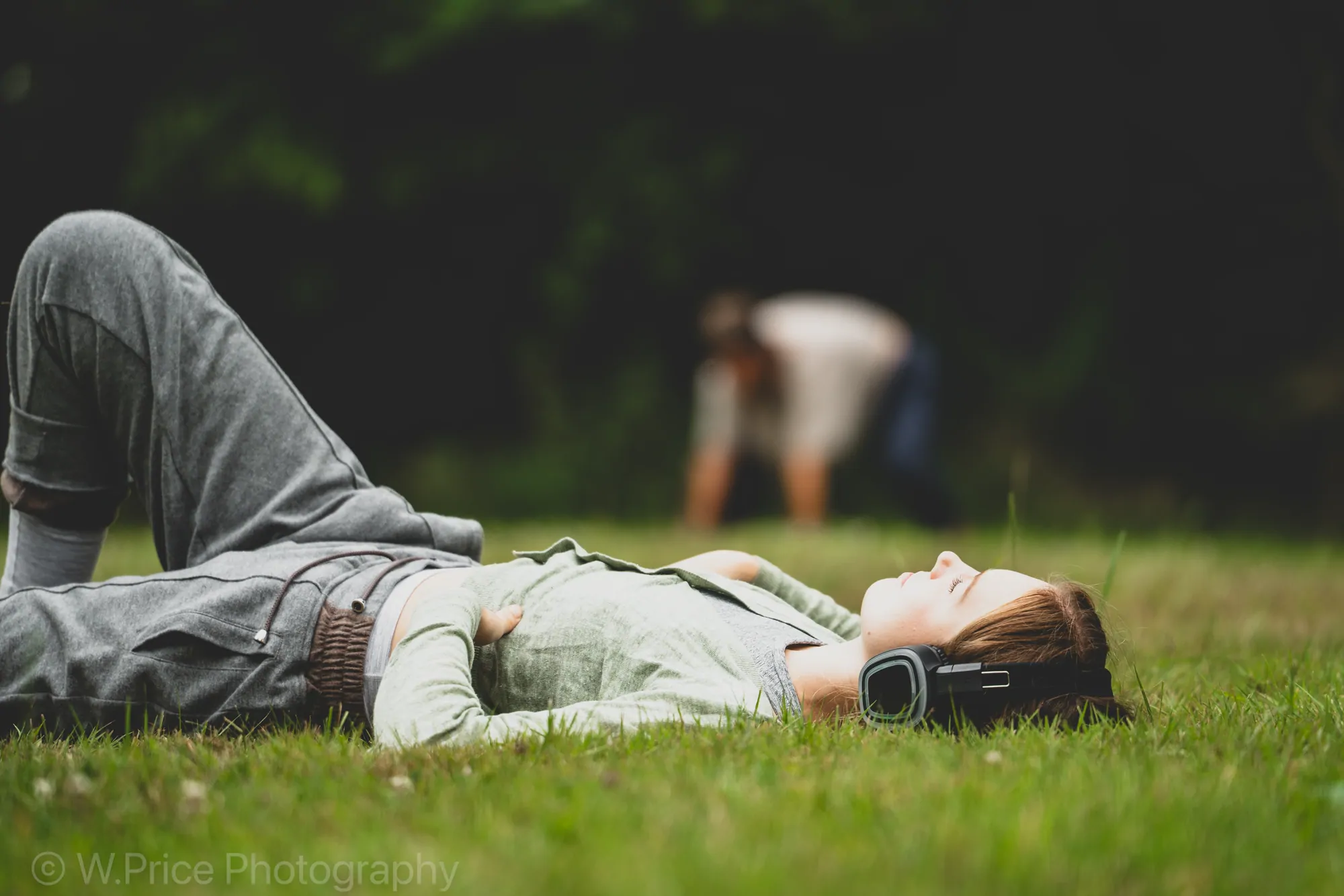 A guest lying back on the grass, eyes closed, during a rest practice