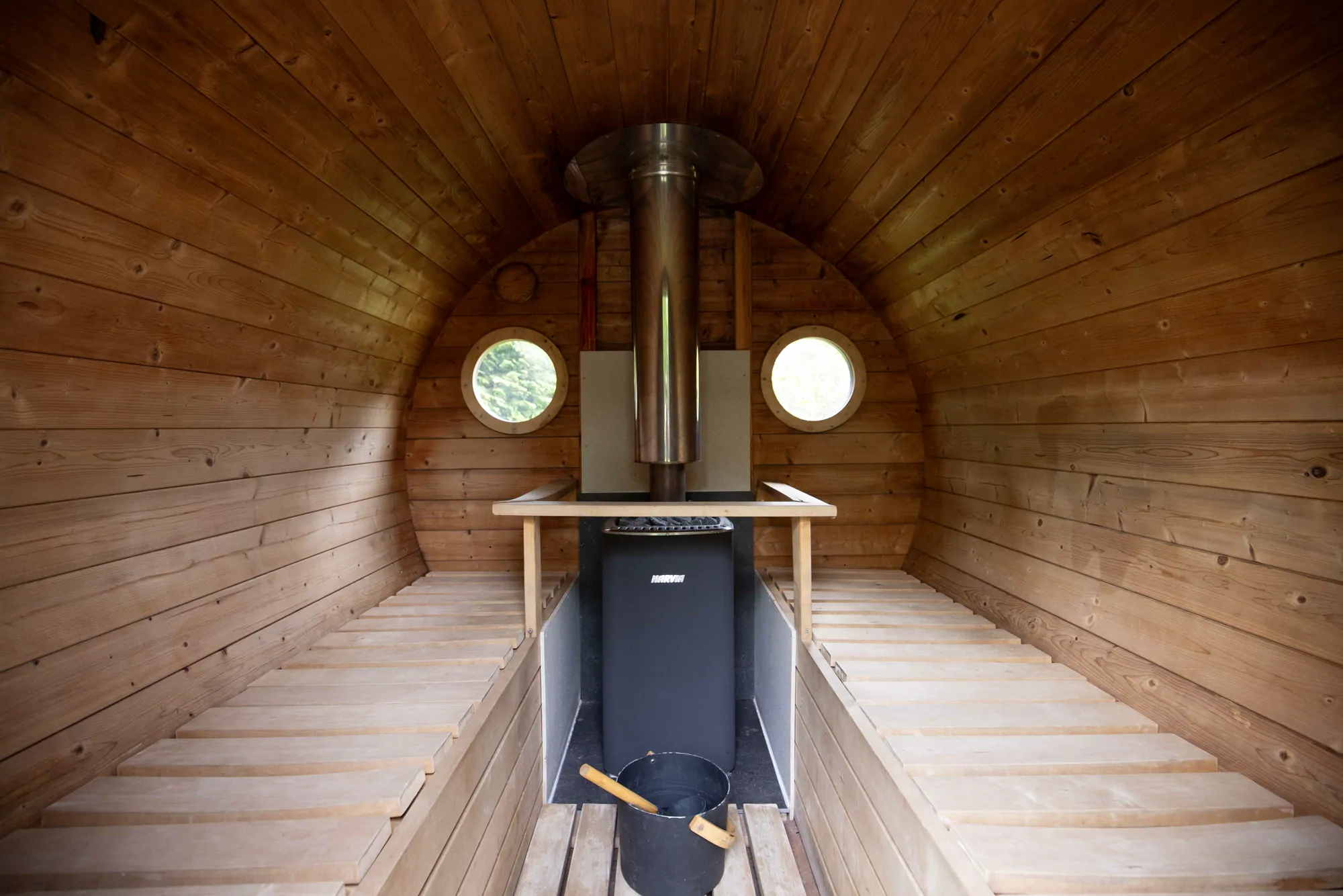 Inside the barrel sauna, benches either side of the stove