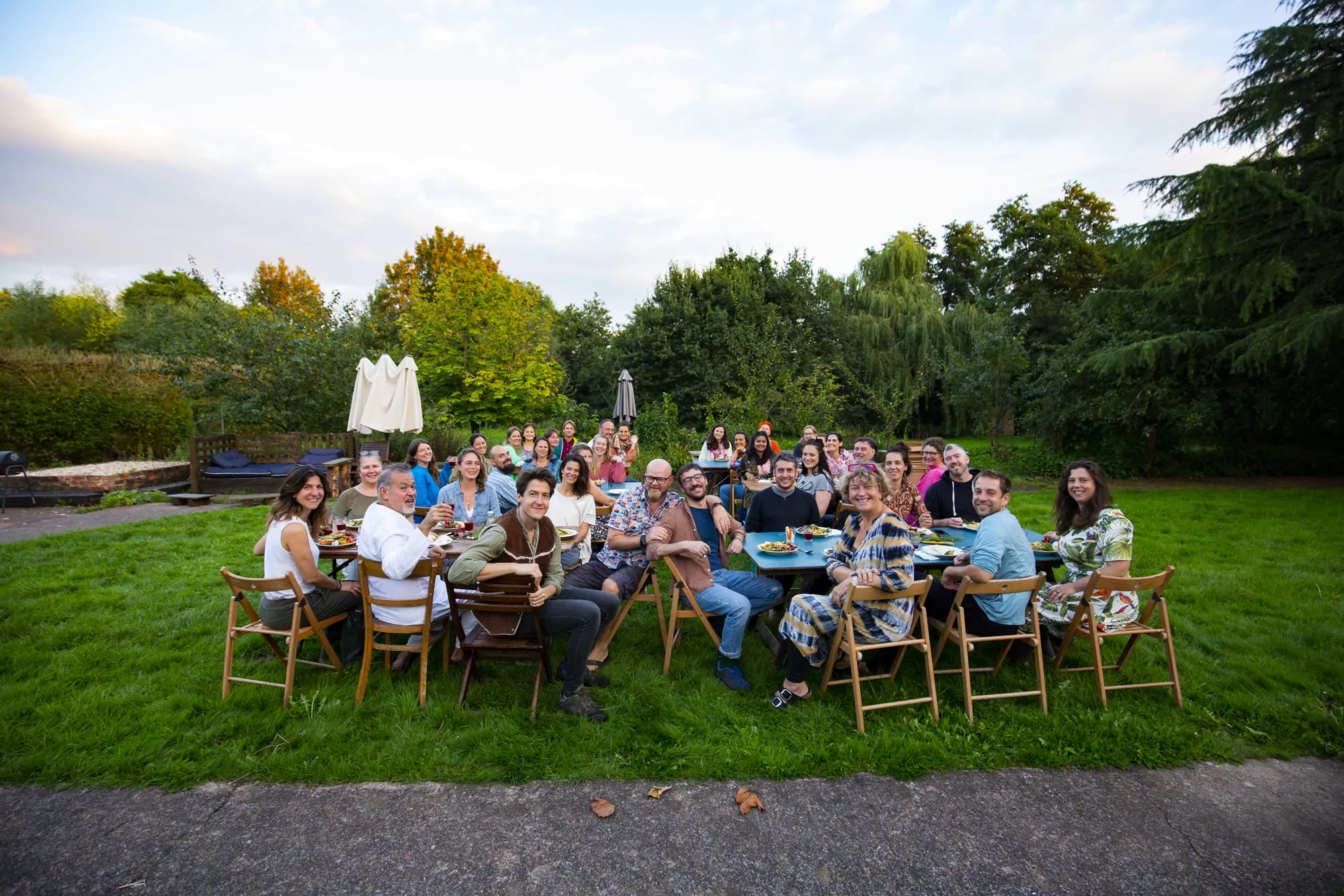 A long garden dinner table with a large group eating together