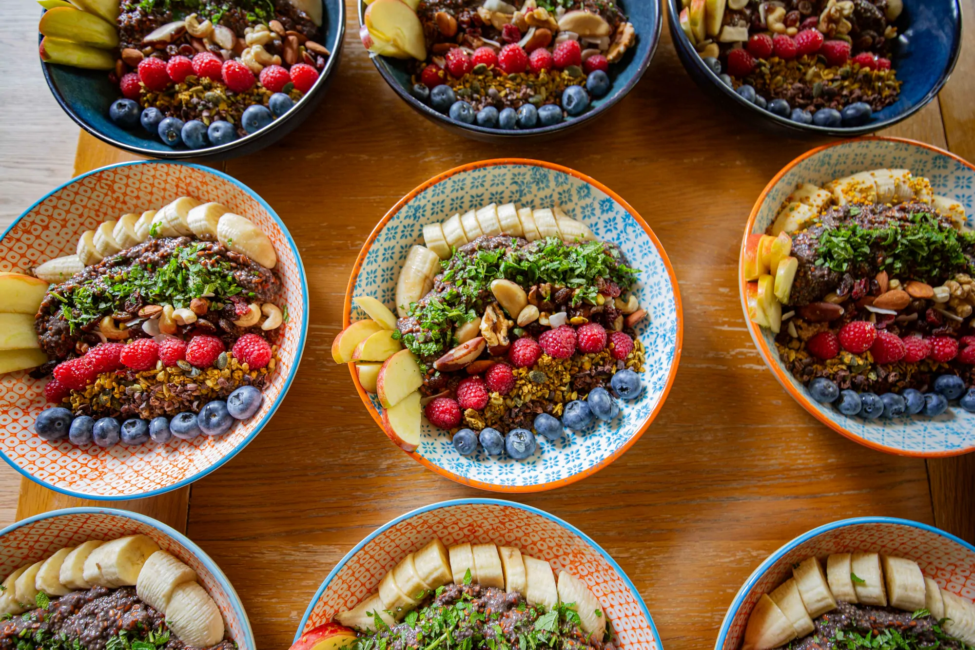 Colourful plant-based bowls laid out along a wooden table