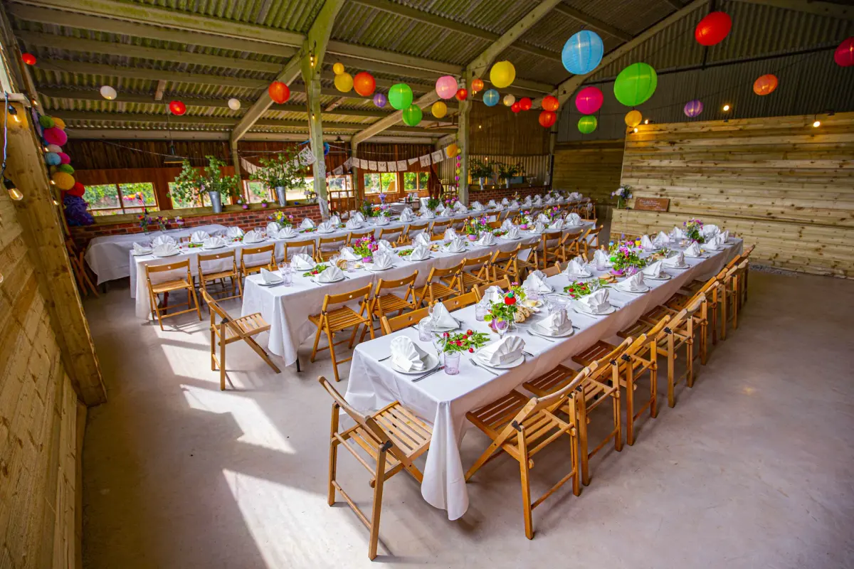 Long tables laid under paper lanterns in the barn