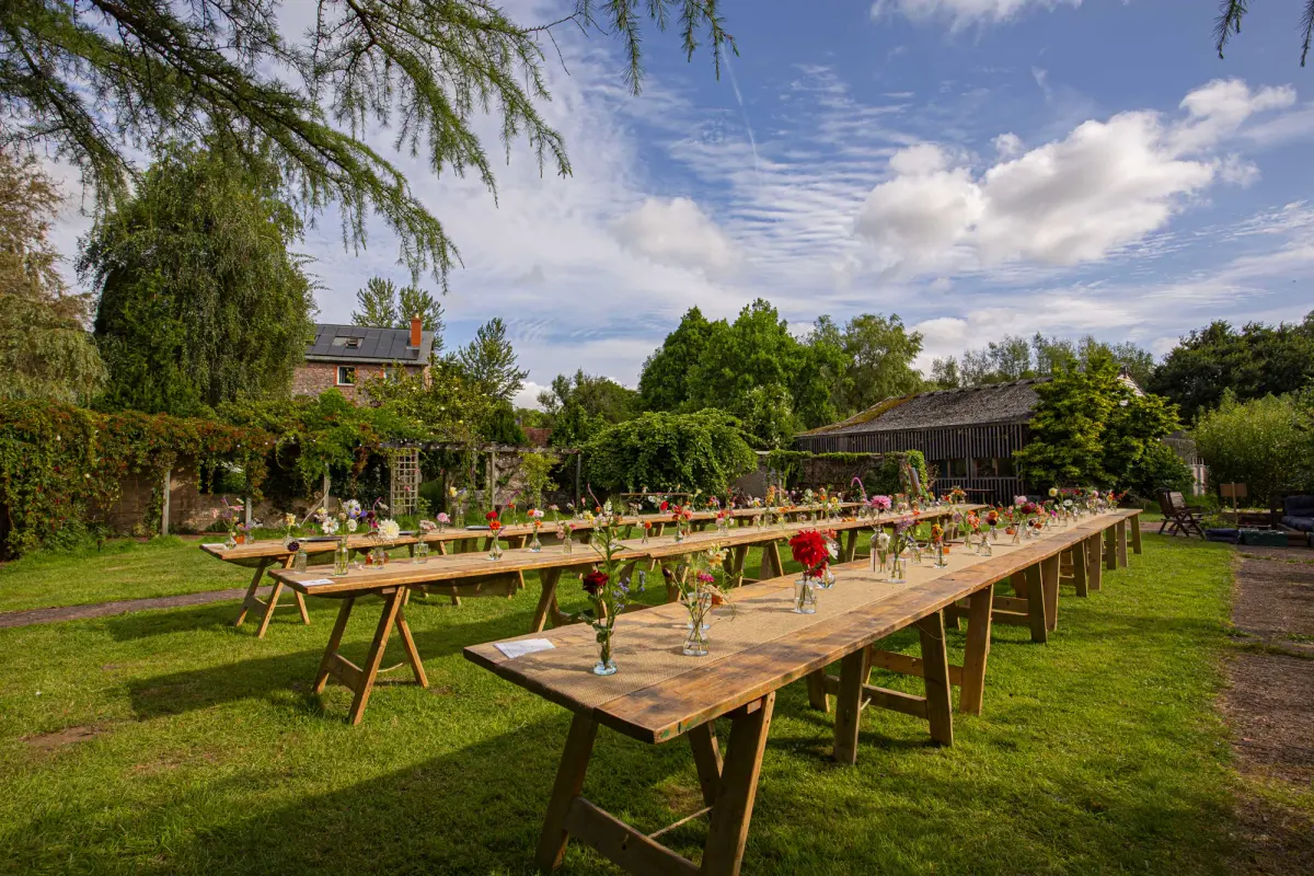 Long trestle tables laid with flowers on the lawn