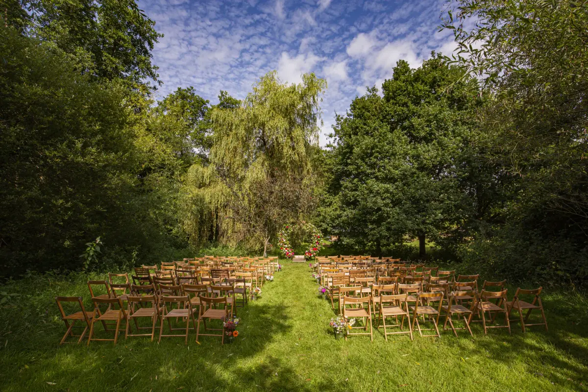 Rows of chairs set out in the meadow facing the willow