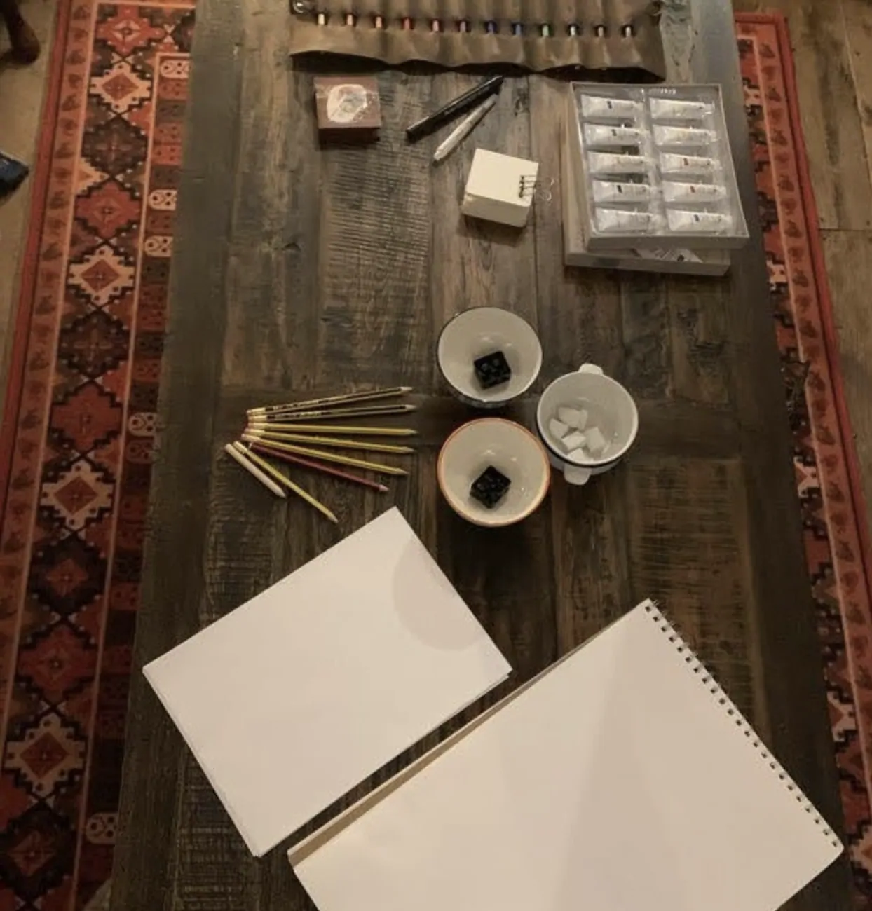 Paints and sketchbooks laid out for an evening of drawing